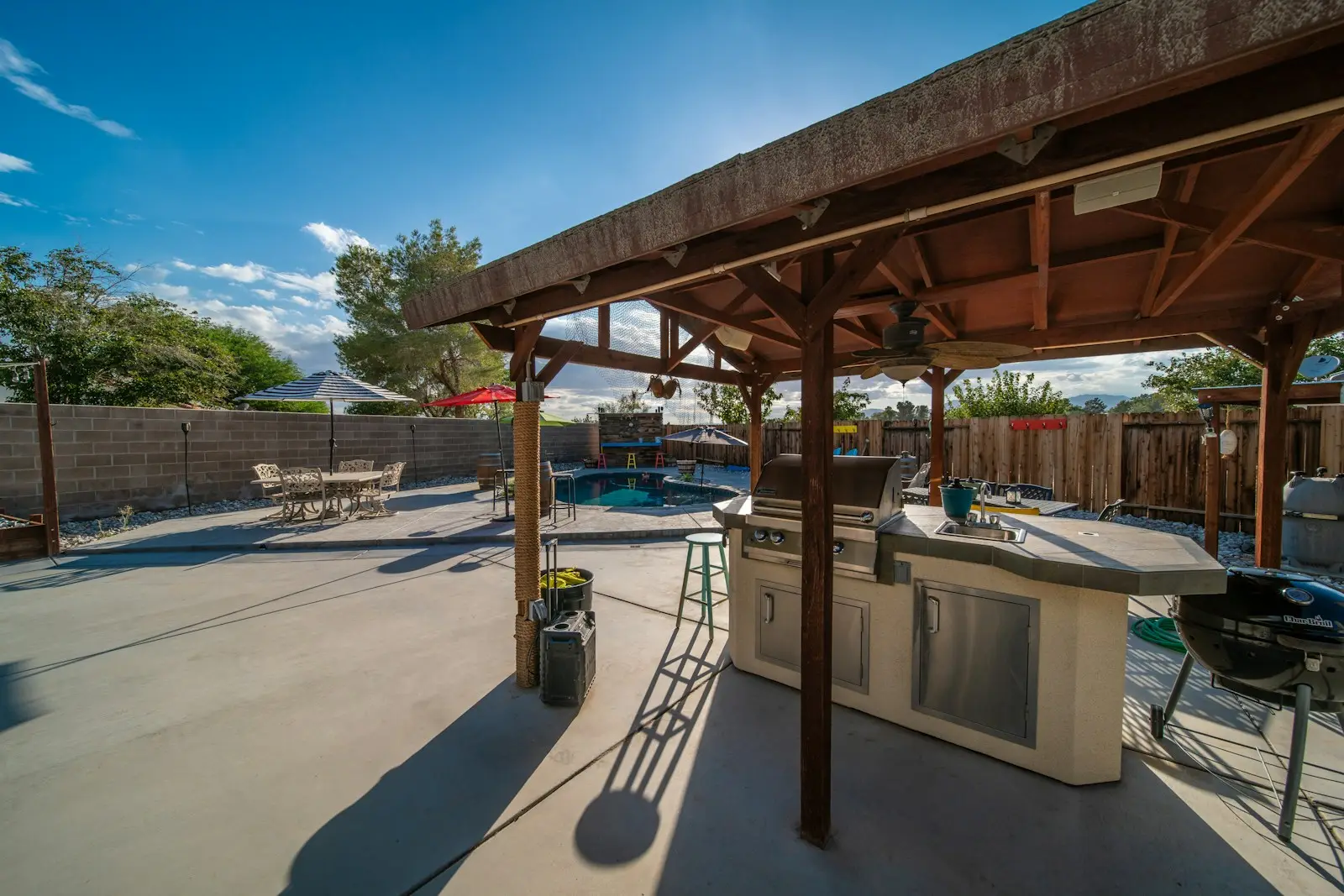 Reference: covered backyard patio with wood pergola, BBQ island, and concrete slab